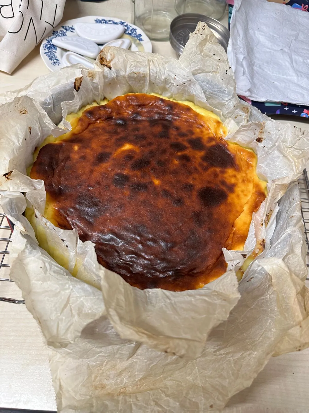 A whole Basque burnt cheesecake, deep caramel-brown on top, cooling on a wire rack
